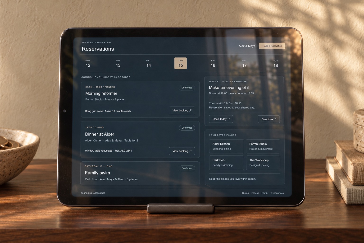 Close-up of an iPad mini on the walnut console, showing dining, fitness and family reservations.